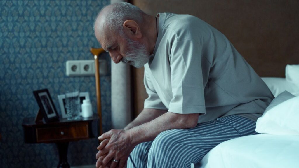 Elderly man sitting on the bed sad and tired unable to sleep